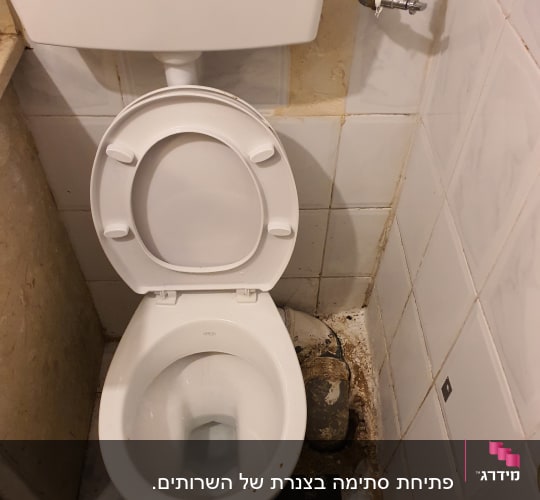 אסלה עם צינור מים וברז ליד הקיר